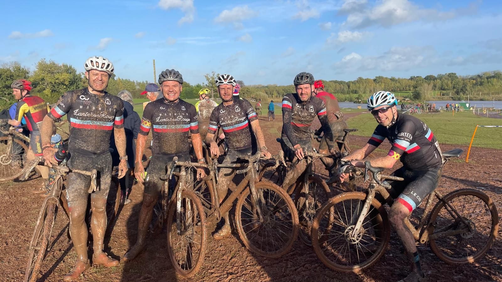 4 very muddy men posing with their bikes at the finish